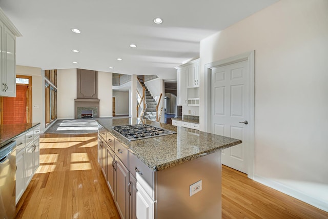 kitchen featuring appliances with stainless steel finishes, a center island, light hardwood / wood-style floors, and white cabinetry