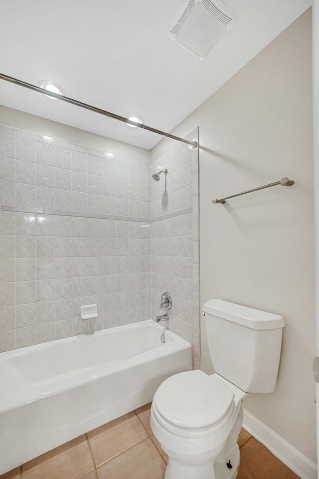 bathroom with tile patterned flooring, tiled shower / bath, and toilet