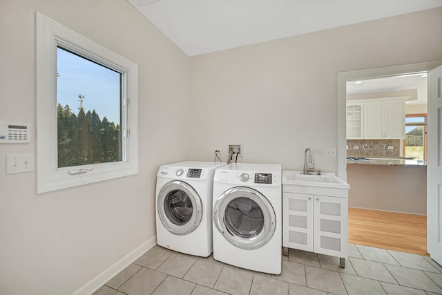 clothes washing area featuring washer and clothes dryer, sink, and light tile patterned floors