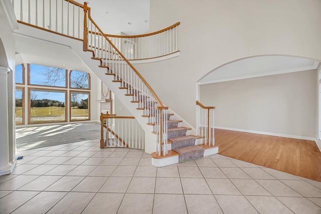 staircase with tile patterned floors and a high ceiling