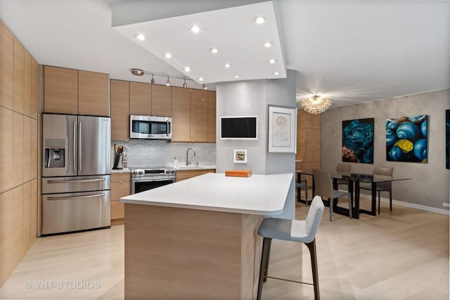 kitchen with a breakfast bar, high vaulted ceiling, stainless steel appliances, a center island, and decorative backsplash