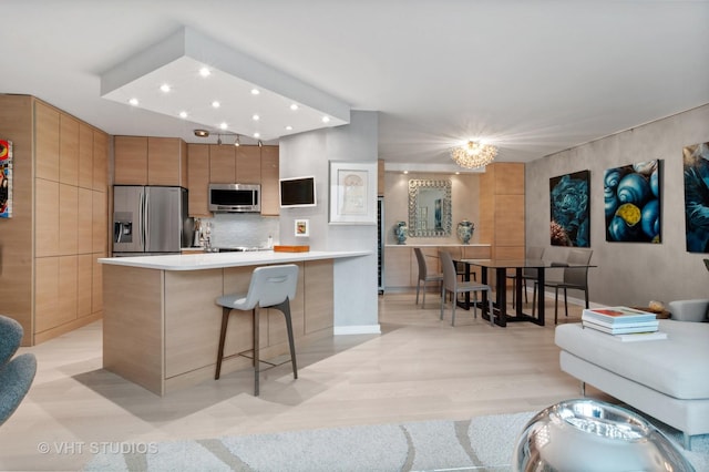 kitchen featuring a breakfast bar, tasteful backsplash, light wood-type flooring, stainless steel appliances, and a large island