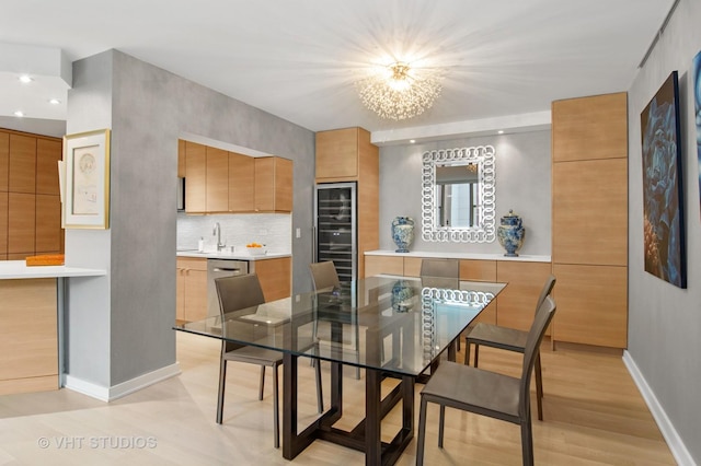 dining space with wine cooler, sink, and light hardwood / wood-style flooring