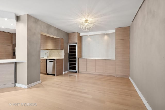 kitchen featuring sink, light hardwood / wood-style flooring, tasteful backsplash, stainless steel dishwasher, and beverage cooler