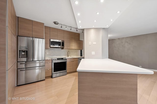 kitchen with sink, tasteful backsplash, high vaulted ceiling, light wood-type flooring, and appliances with stainless steel finishes