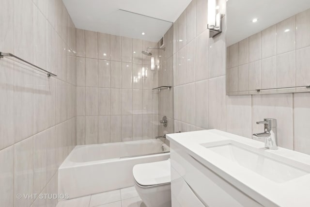 full bathroom with tiled shower / bath, vanity, and tile walls