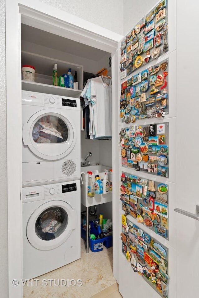 laundry area featuring stacked washer / dryer and light tile patterned floors