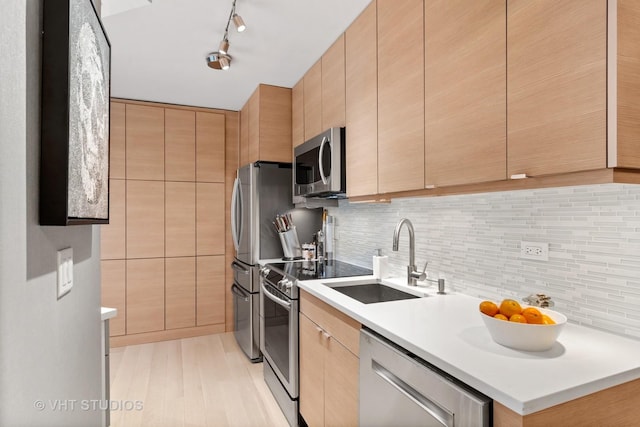 kitchen featuring sink, light brown cabinets, track lighting, stainless steel appliances, and backsplash