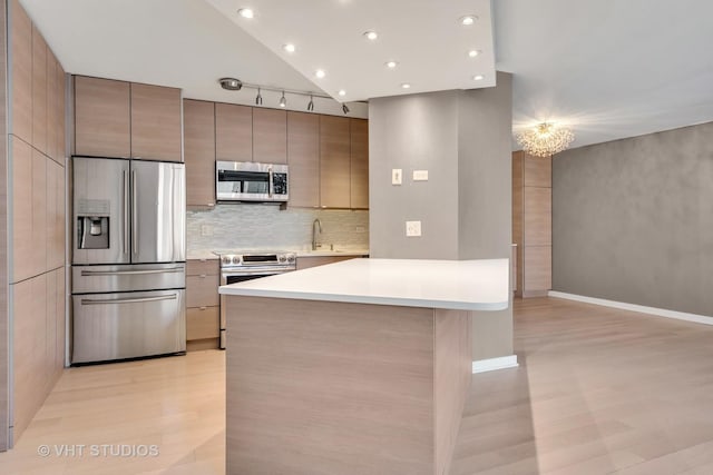 kitchen featuring appliances with stainless steel finishes, high vaulted ceiling, sink, backsplash, and a chandelier