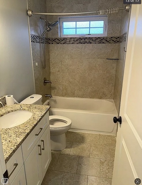 full bathroom featuring vanity, tiled shower / bath combo, and toilet