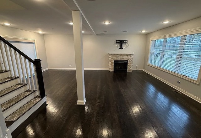 basement featuring dark hardwood / wood-style floors and a stone fireplace