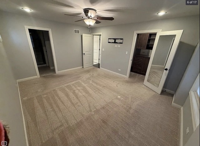 unfurnished bedroom featuring ceiling fan, light colored carpet, a spacious closet, and connected bathroom