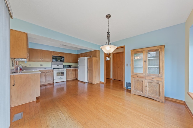 kitchen with pendant lighting, light hardwood / wood-style floors, white appliances, and sink