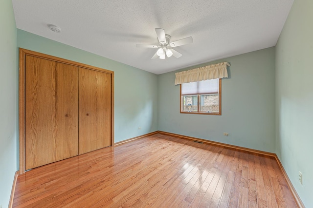 unfurnished bedroom with ceiling fan, a closet, a textured ceiling, and light wood-type flooring