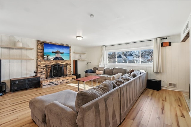 living room featuring a brick fireplace and light hardwood / wood-style floors