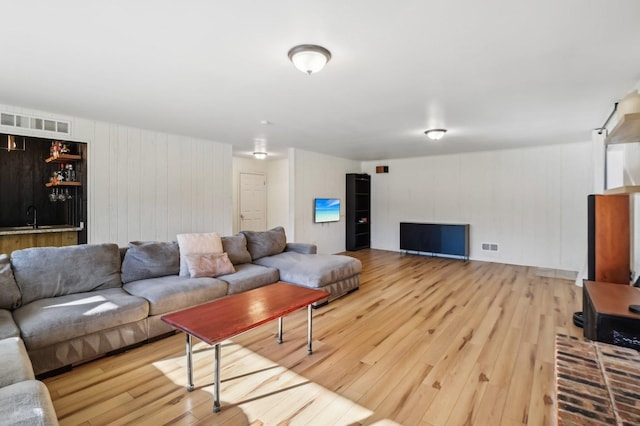 living room with wet bar and light hardwood / wood-style floors