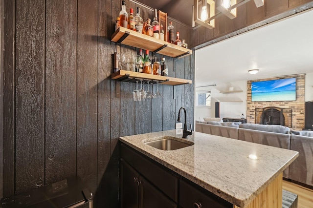 kitchen with sink, light hardwood / wood-style flooring, and light stone countertops