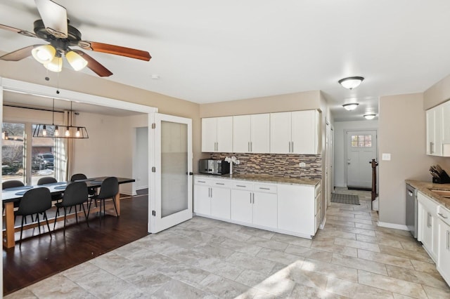 kitchen featuring light stone counters, stainless steel dishwasher, and white cabinets