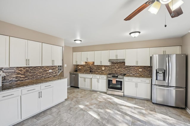 kitchen featuring ceiling fan, stainless steel appliances, white cabinets, decorative backsplash, and dark stone counters