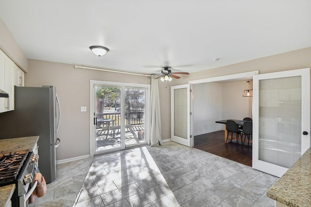 kitchen featuring white cabinetry, stainless steel gas stove, light stone countertops, and french doors