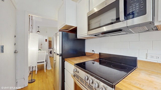 kitchen with stainless steel appliances, light wood-type flooring, wood counters, backsplash, and white cabinetry