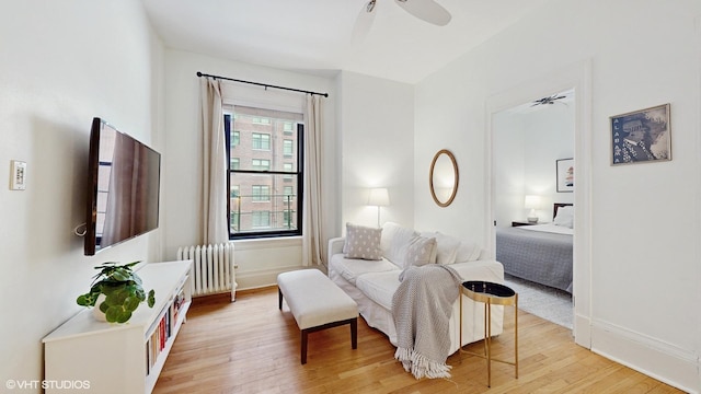 living area with ceiling fan, light hardwood / wood-style flooring, and radiator