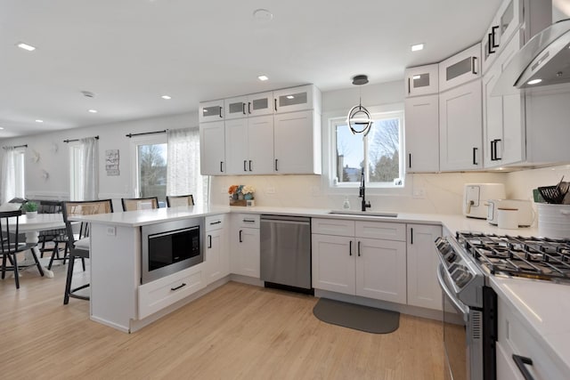 kitchen featuring sink, white cabinetry, kitchen peninsula, pendant lighting, and appliances with stainless steel finishes