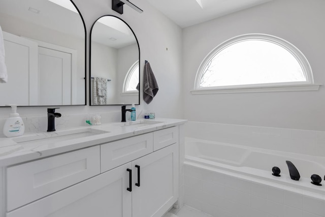 bathroom with vanity, tiled bath, and plenty of natural light