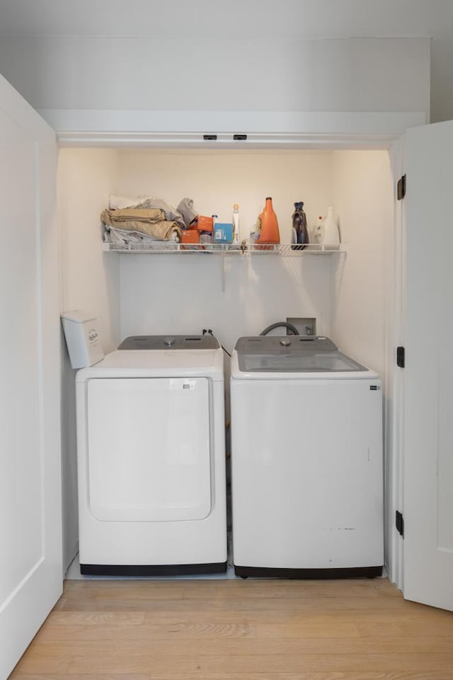 laundry area featuring separate washer and dryer and light hardwood / wood-style flooring