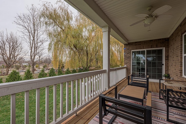 wooden terrace with a lawn and ceiling fan