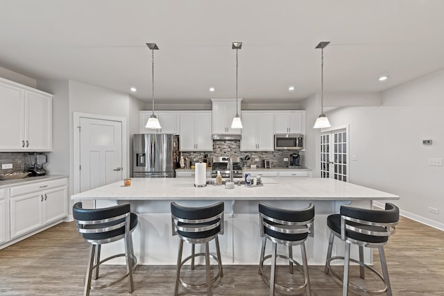 kitchen featuring pendant lighting, stainless steel appliances, white cabinetry, and a spacious island