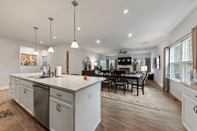 kitchen featuring a kitchen island with sink, white cabinets, sink, stainless steel dishwasher, and ceiling fan