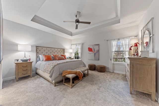 carpeted bedroom with a tray ceiling, multiple windows, ceiling fan, and crown molding