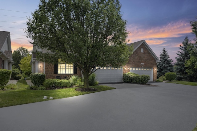 view of property hidden behind natural elements featuring a garage and a lawn