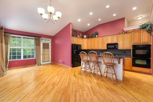 kitchen featuring lofted ceiling, an inviting chandelier, black appliances, light hardwood / wood-style flooring, and a kitchen bar