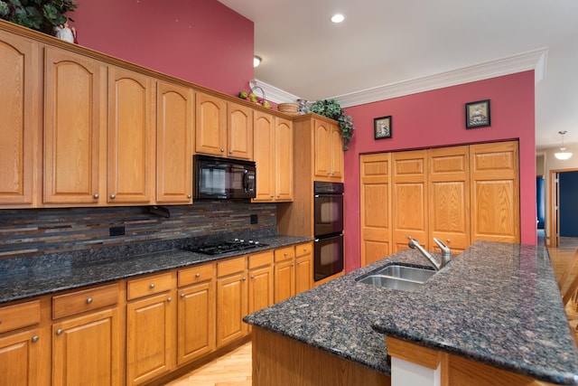 kitchen featuring decorative backsplash, a kitchen island with sink, sink, and black appliances