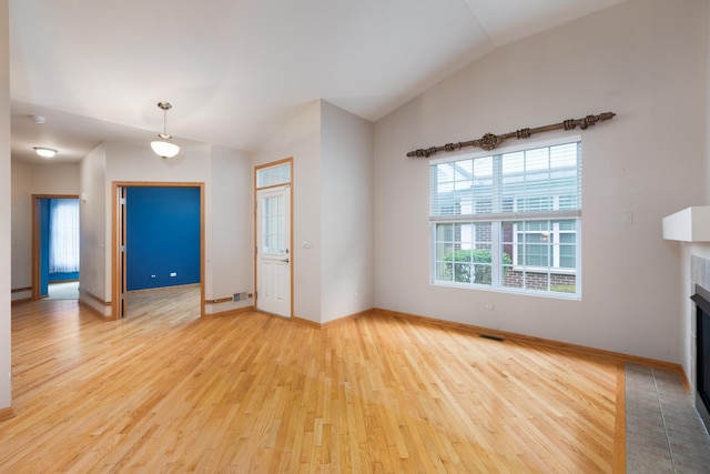 unfurnished living room featuring light wood-type flooring, lofted ceiling, and a fireplace