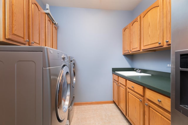 clothes washing area featuring washing machine and clothes dryer, sink, light tile patterned floors, and cabinets