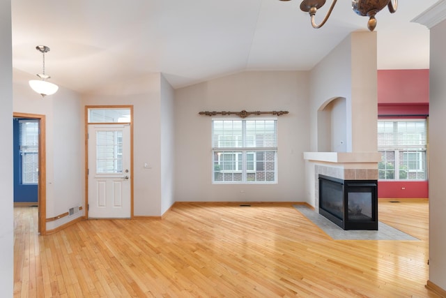 unfurnished living room with a multi sided fireplace, light wood-type flooring, a wealth of natural light, and vaulted ceiling