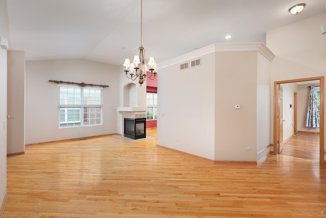 unfurnished living room featuring a notable chandelier, lofted ceiling, a fireplace, and light hardwood / wood-style flooring