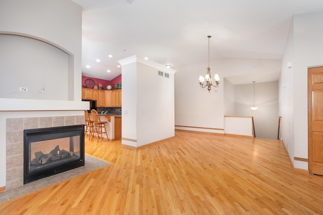 unfurnished living room featuring a fireplace, a chandelier, light hardwood / wood-style flooring, and lofted ceiling