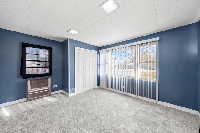 unfurnished bedroom featuring carpet, heating unit, and a closet