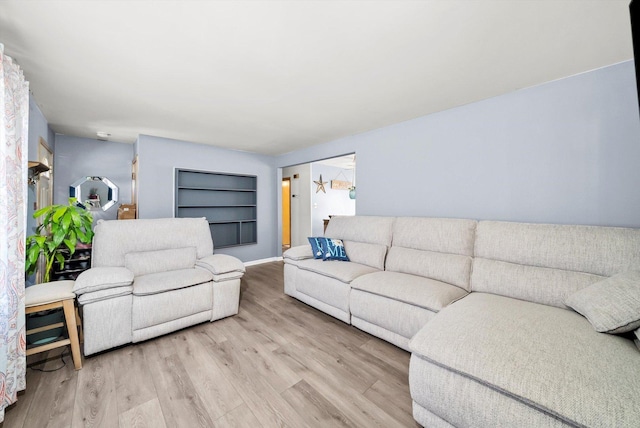 living room with built in shelves and light hardwood / wood-style floors