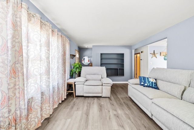 living room with light hardwood / wood-style floors and built in shelves