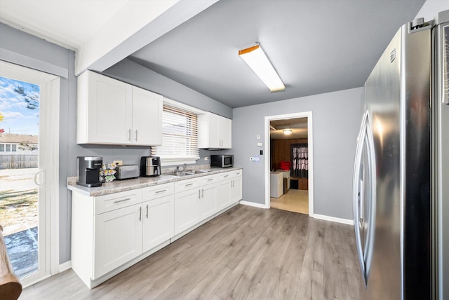 kitchen featuring appliances with stainless steel finishes, white cabinetry, sink, light stone counters, and light wood-type flooring