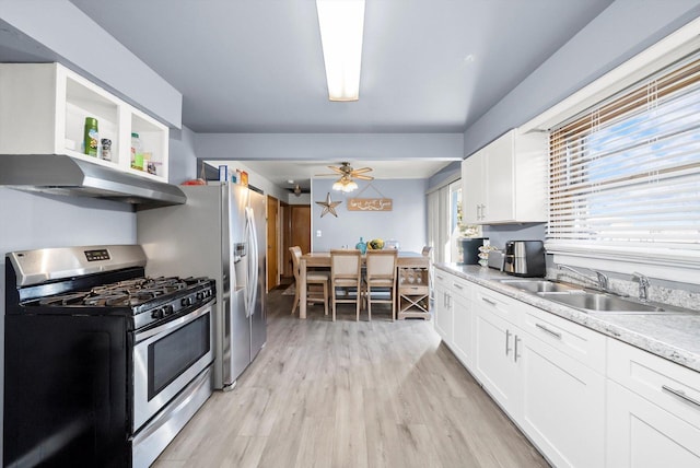 kitchen featuring sink, ceiling fan, white cabinetry, gas range, and light wood-type flooring