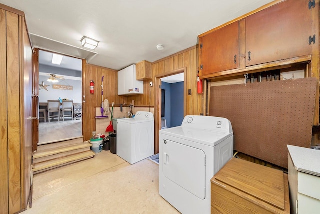 laundry area featuring ceiling fan, wooden walls, cabinets, and washing machine and clothes dryer