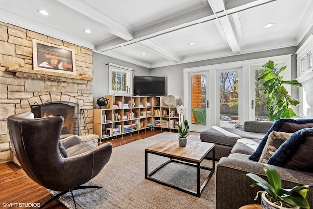 living room featuring a stone fireplace, coffered ceiling, beamed ceiling, and hardwood / wood-style flooring