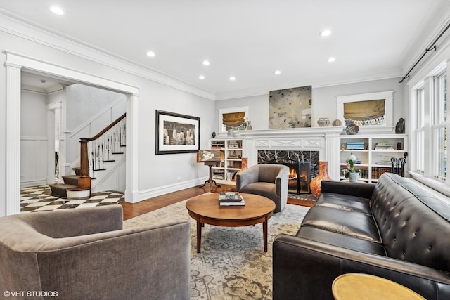 living room with ornamental molding, light wood-type flooring, and a high end fireplace