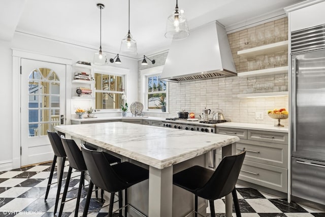 kitchen with decorative light fixtures, custom range hood, gray cabinets, a breakfast bar, and appliances with stainless steel finishes